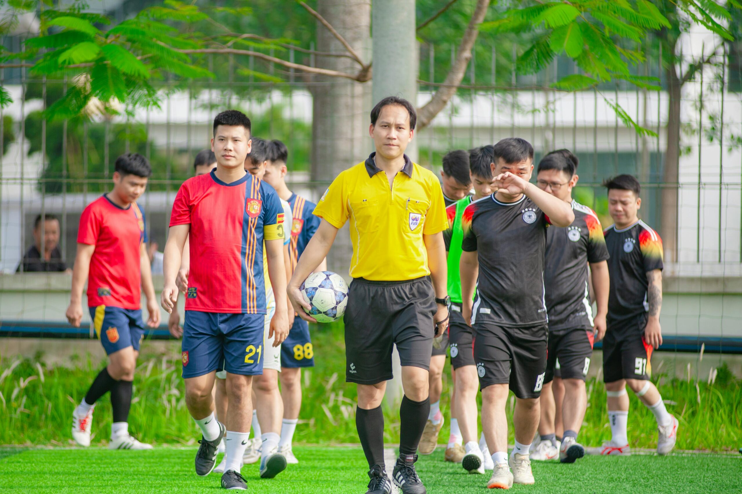 Fußballmannschaften betreten mit ihrem Schiedsrichter das Spielfeld in Hanoi, Vietnam, bereit für ein lokales Spiel.